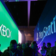 Players walk down an E3 hallway flanked by competing console signs.